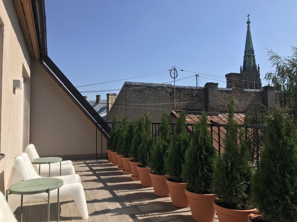 A balcony with a row of potted plants and chairs