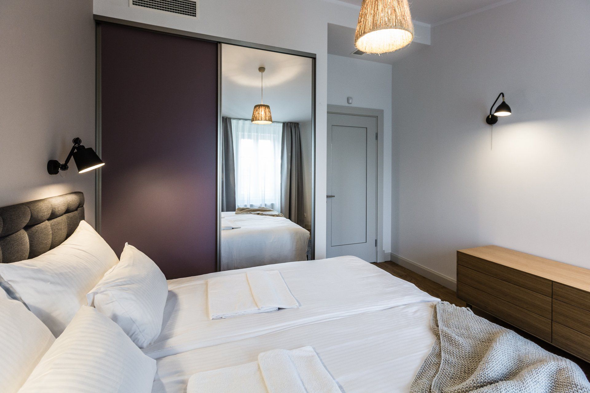 A bedroom with a bed and a large mirror.