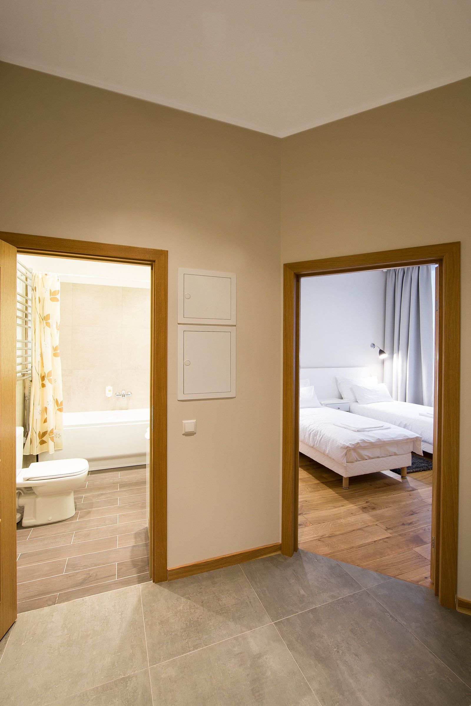 A hallway leading to a bedroom and bathroom in a hotel room.