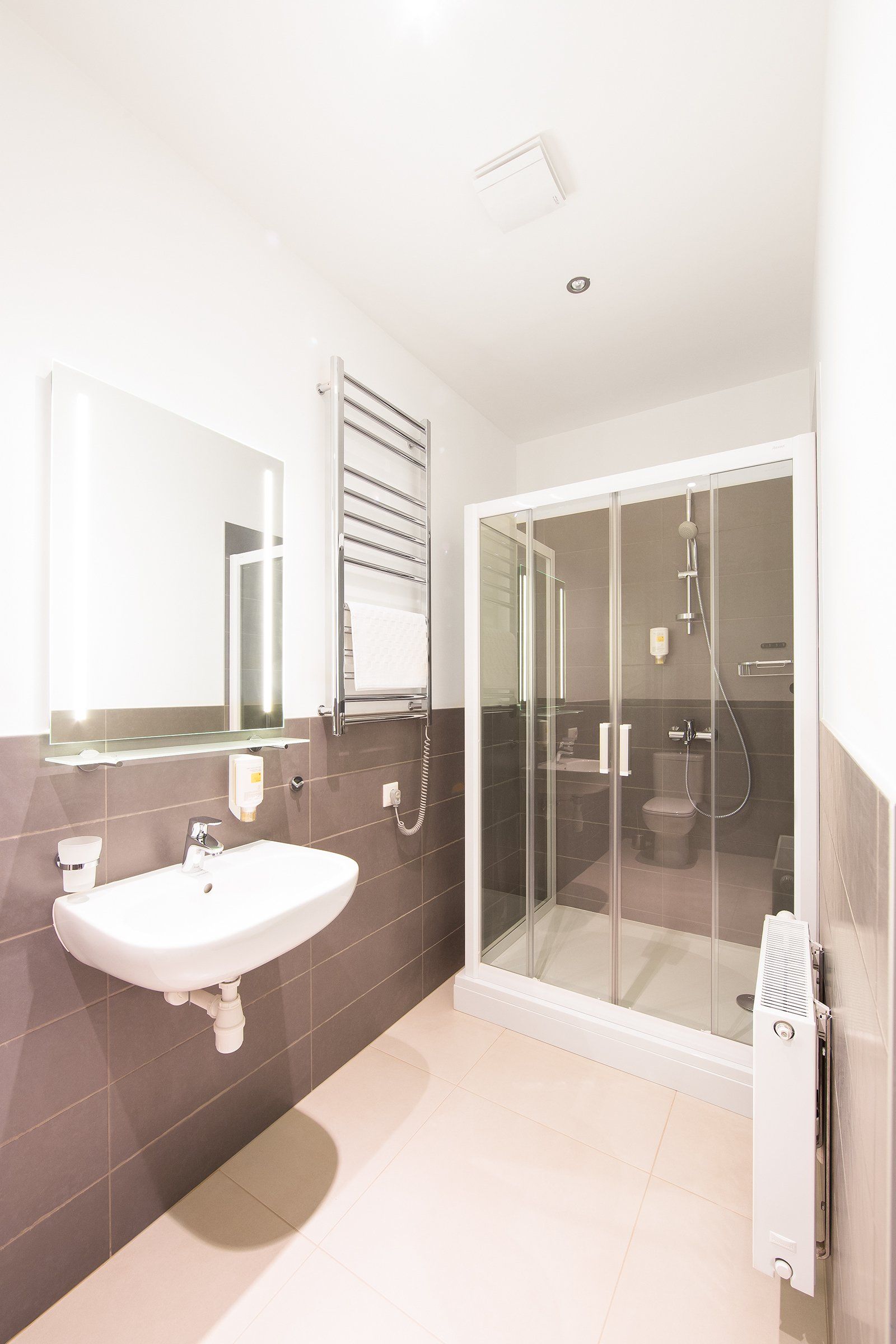 A bathroom with a sink , toilet , shower and mirror.