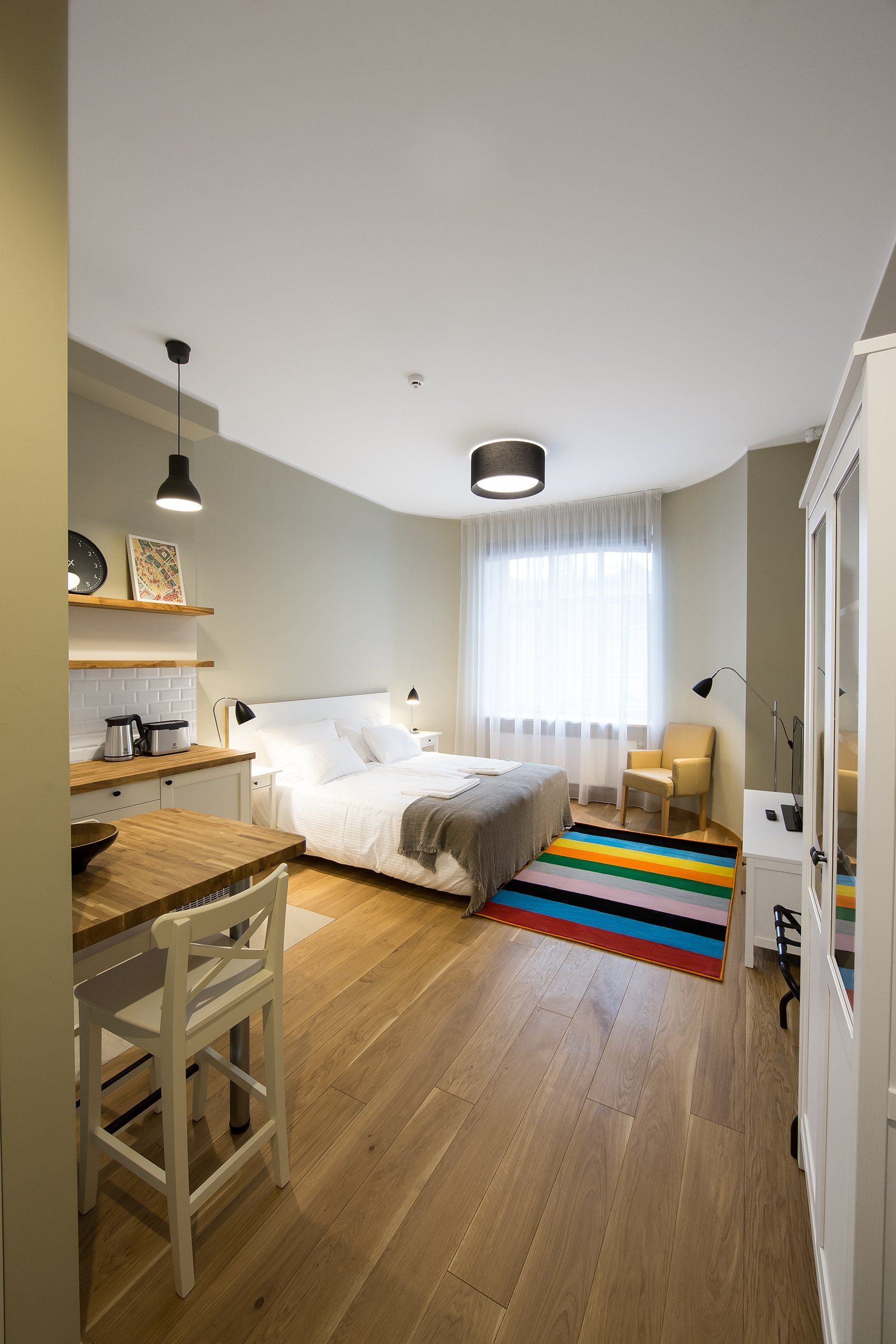 A bedroom with a bed , chair , table and rug.