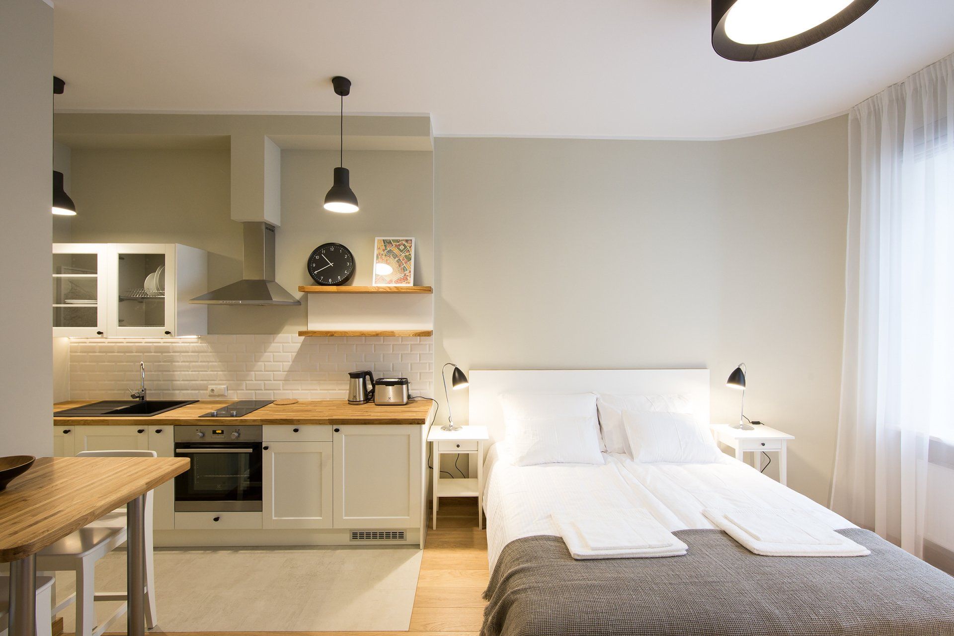 A bedroom with a bed and a kitchen in the background