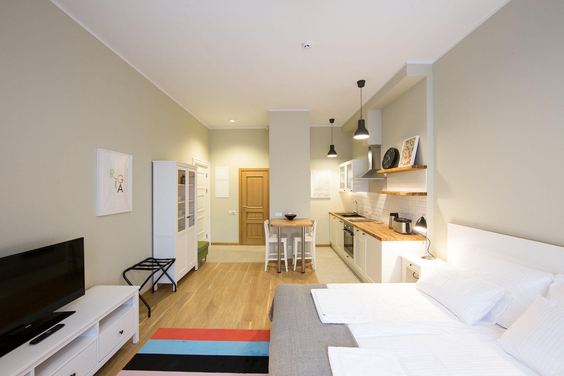 A bedroom with two beds , a television and a kitchen