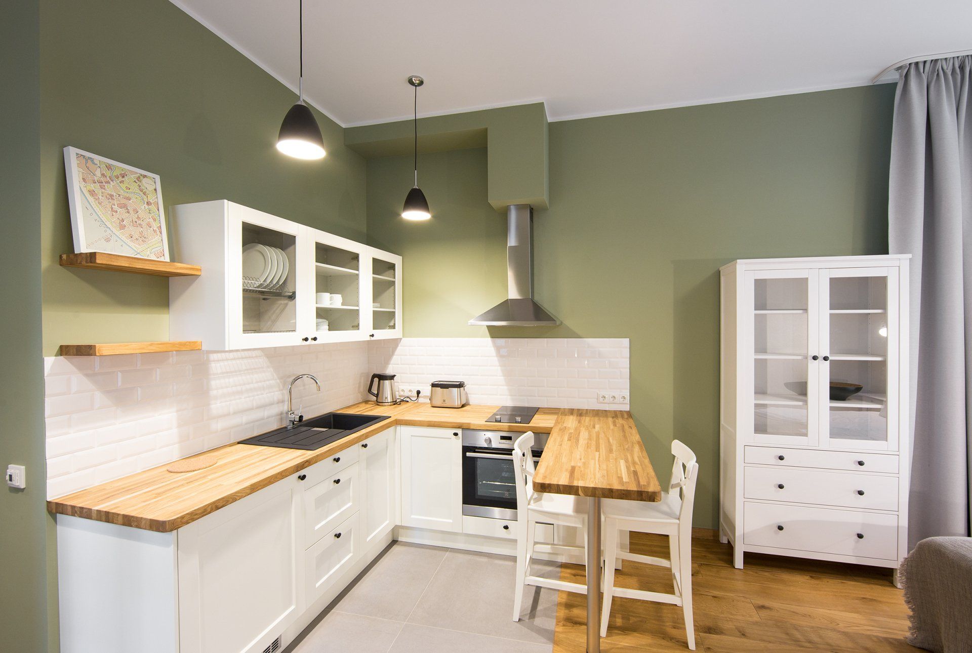A kitchen with white cabinets , wooden counter tops , a table and chairs.