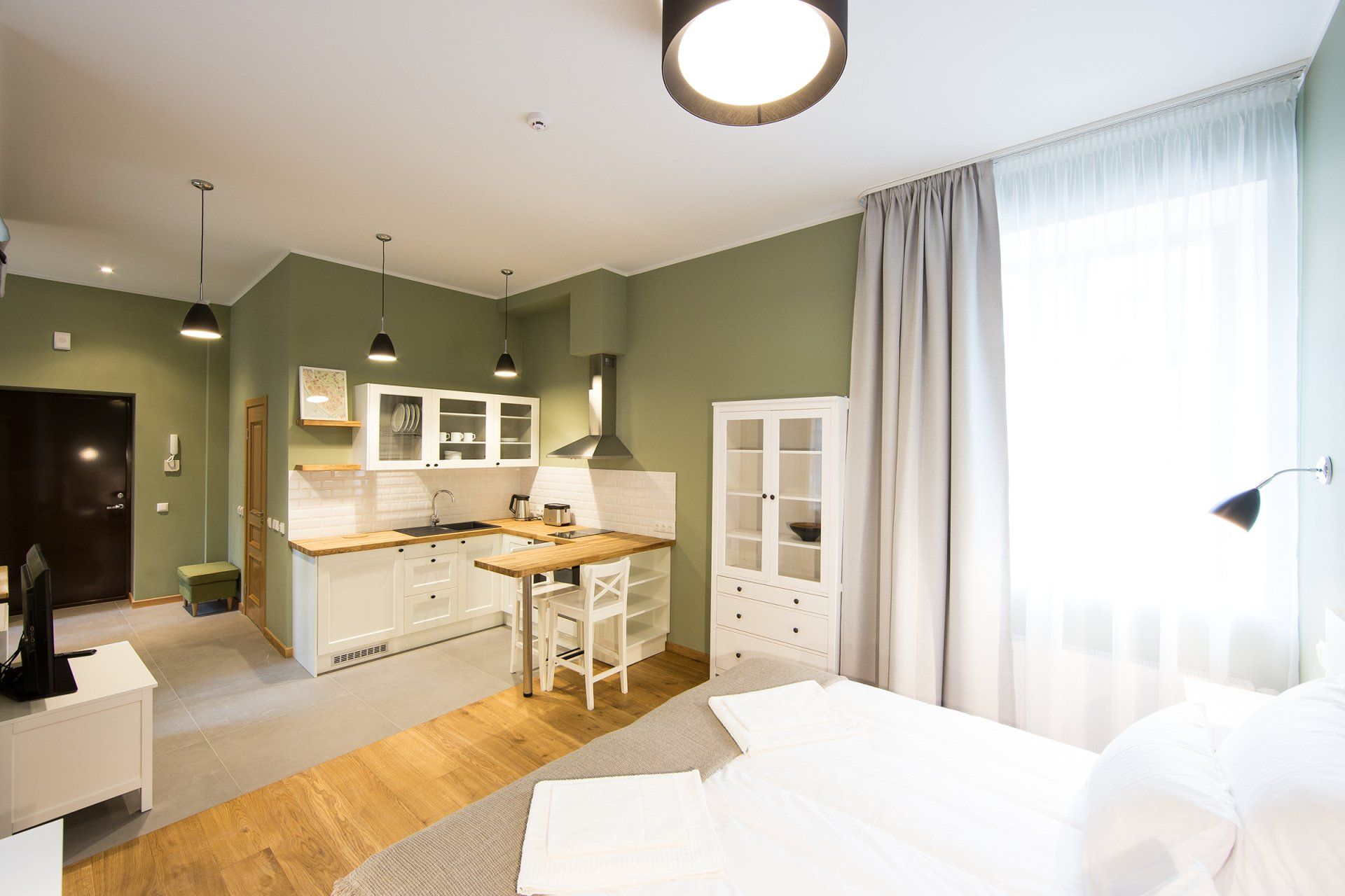 A bedroom with a bed , kitchen , and television.