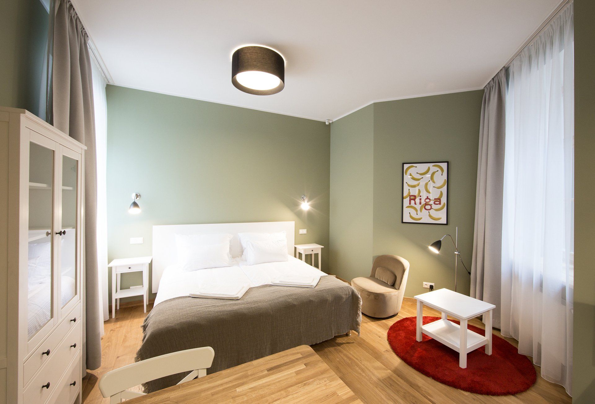 A bedroom with a bed , chair , table and rug.