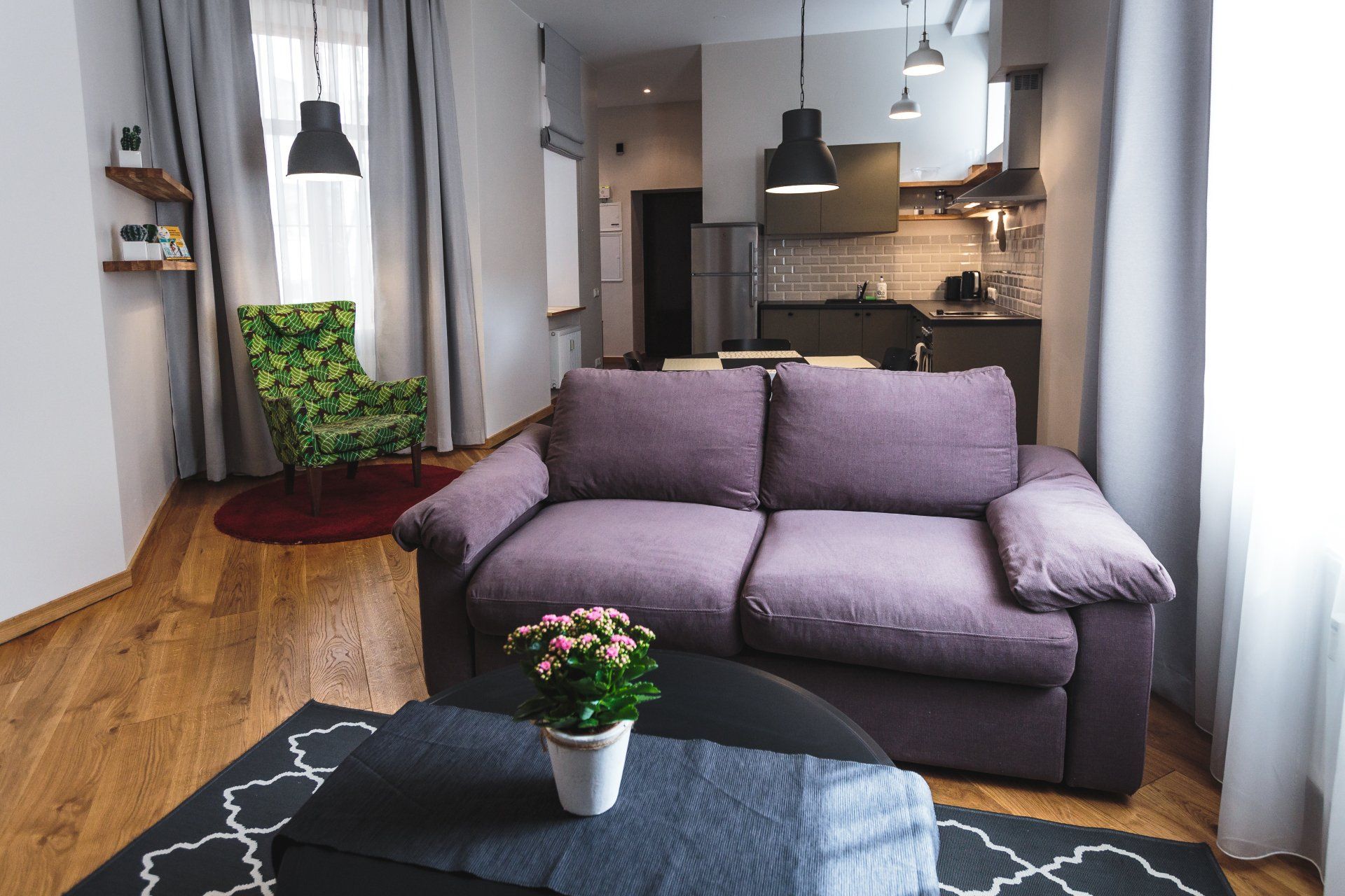 A living room with a purple couch and a green chair