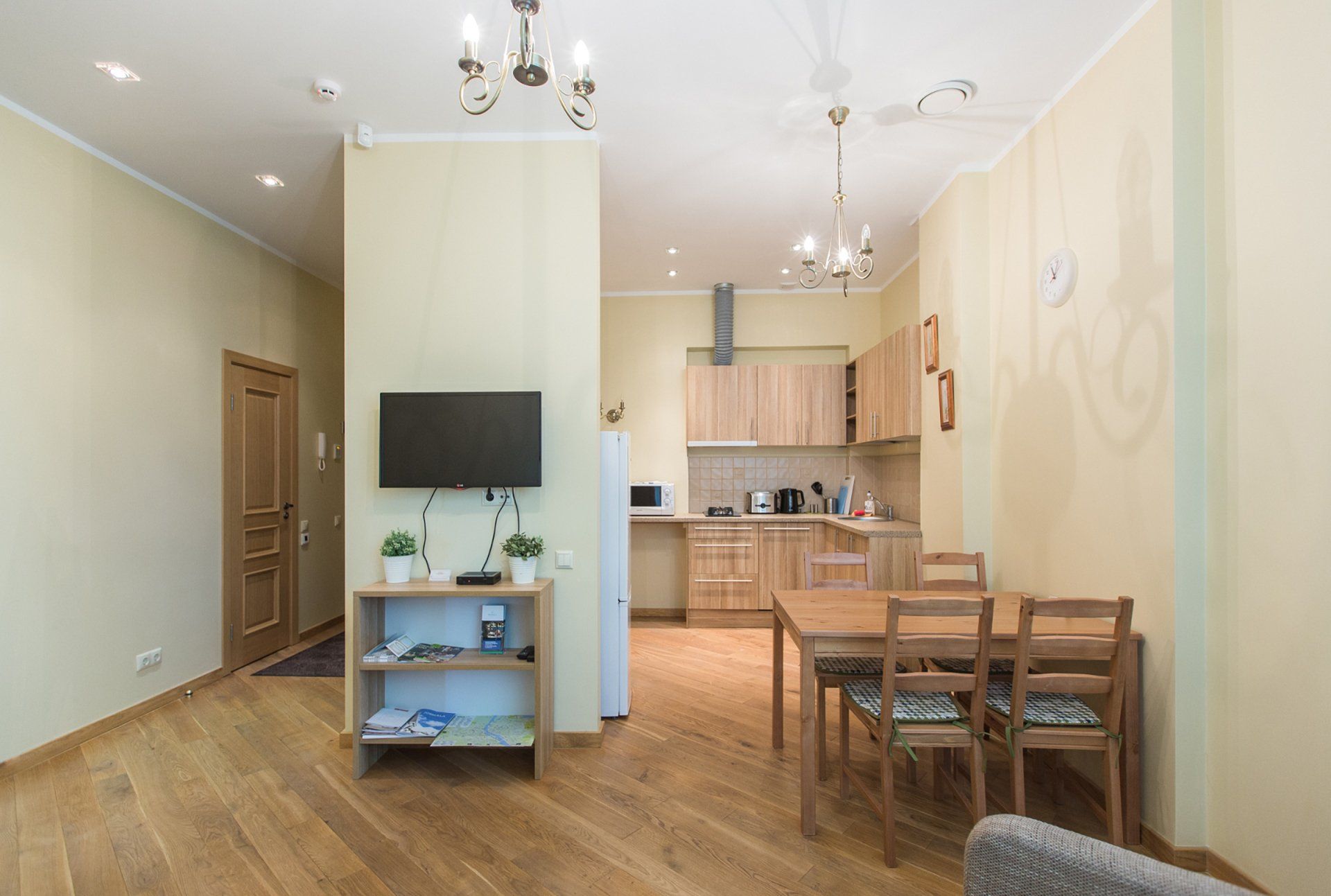 A living room with a dining table and chairs and a flat screen tv.