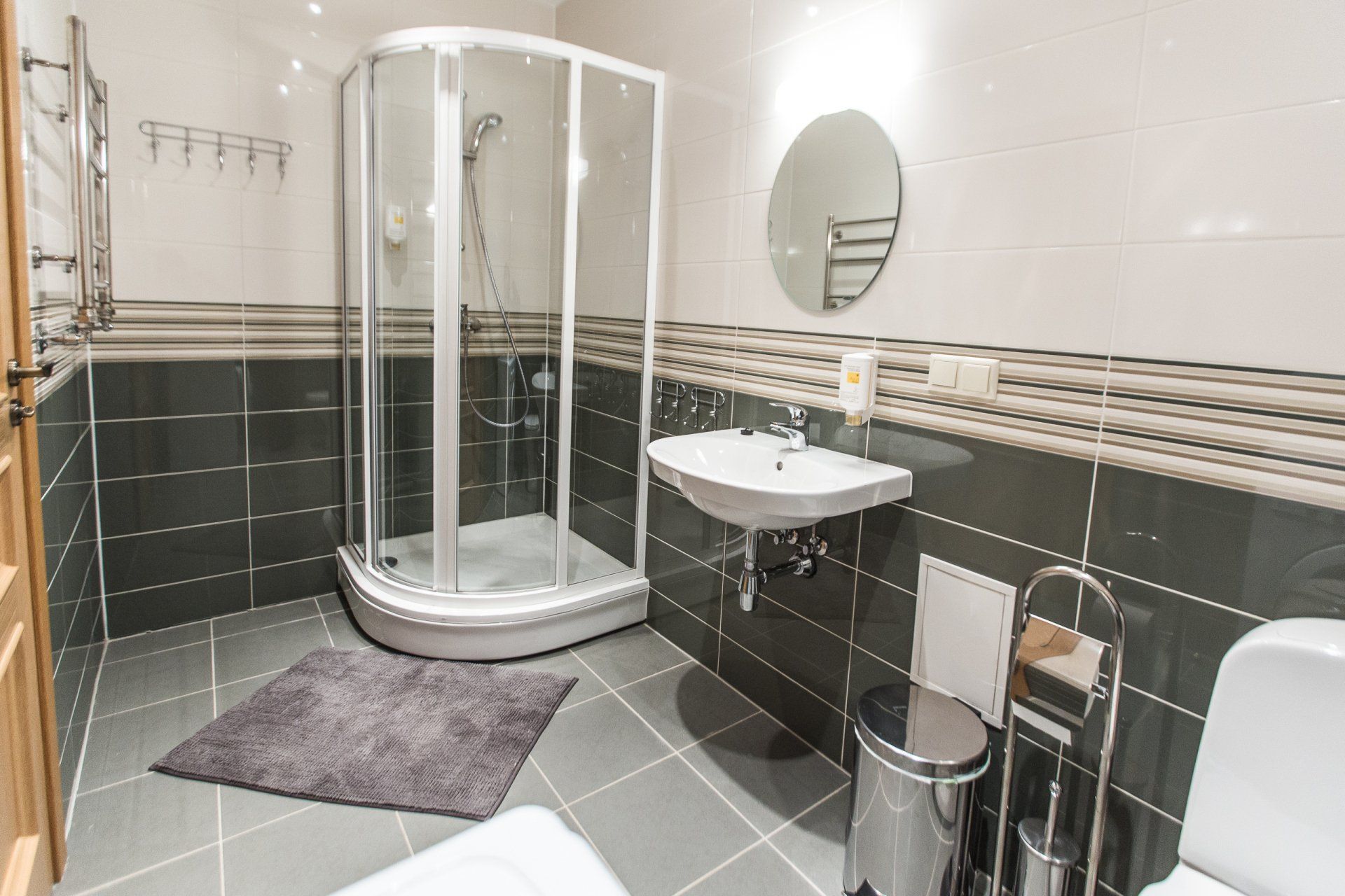 A bathroom with a shower , sink , toilet and mirror.
