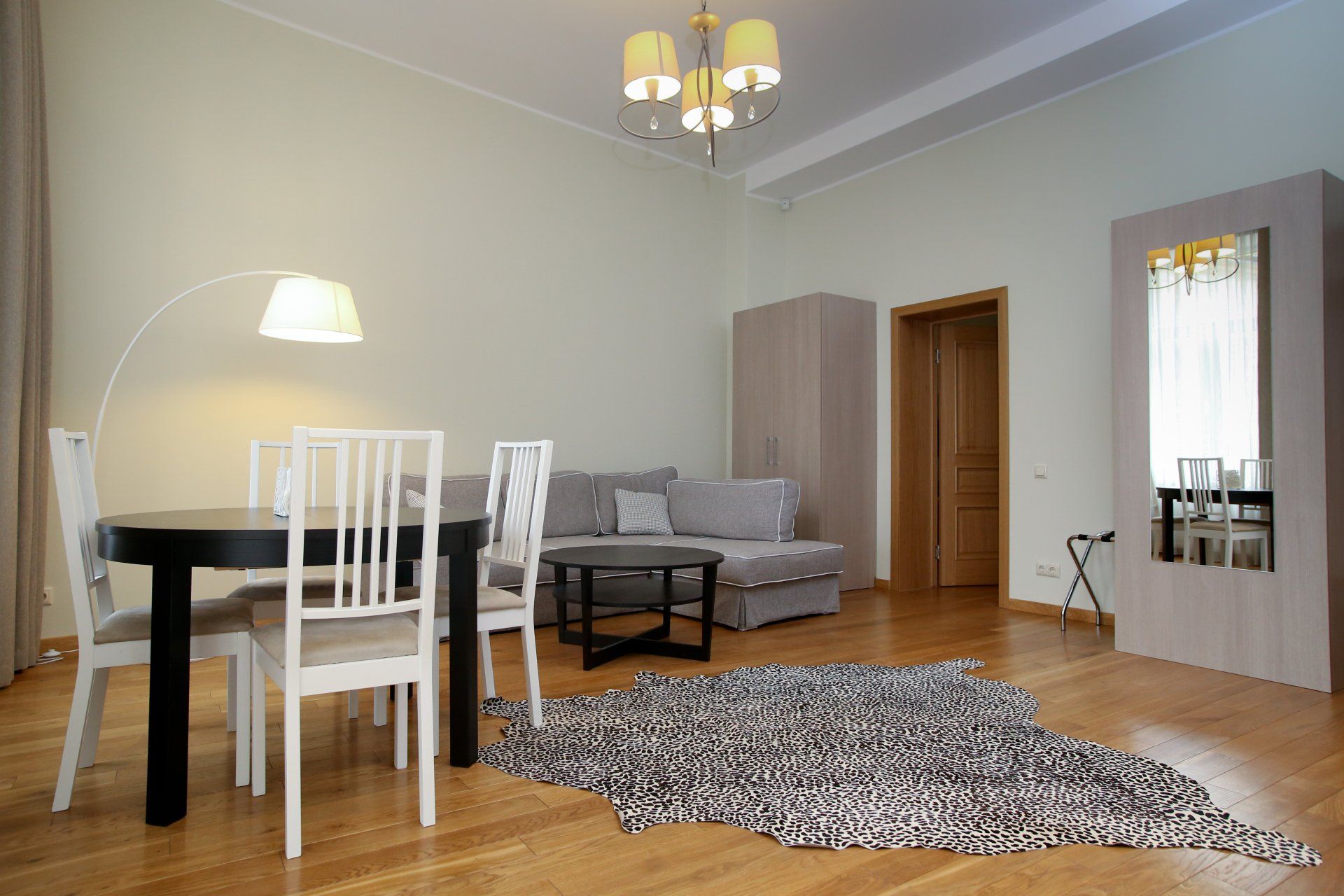 A living room with a dining table and chairs , a couch , and a rug.