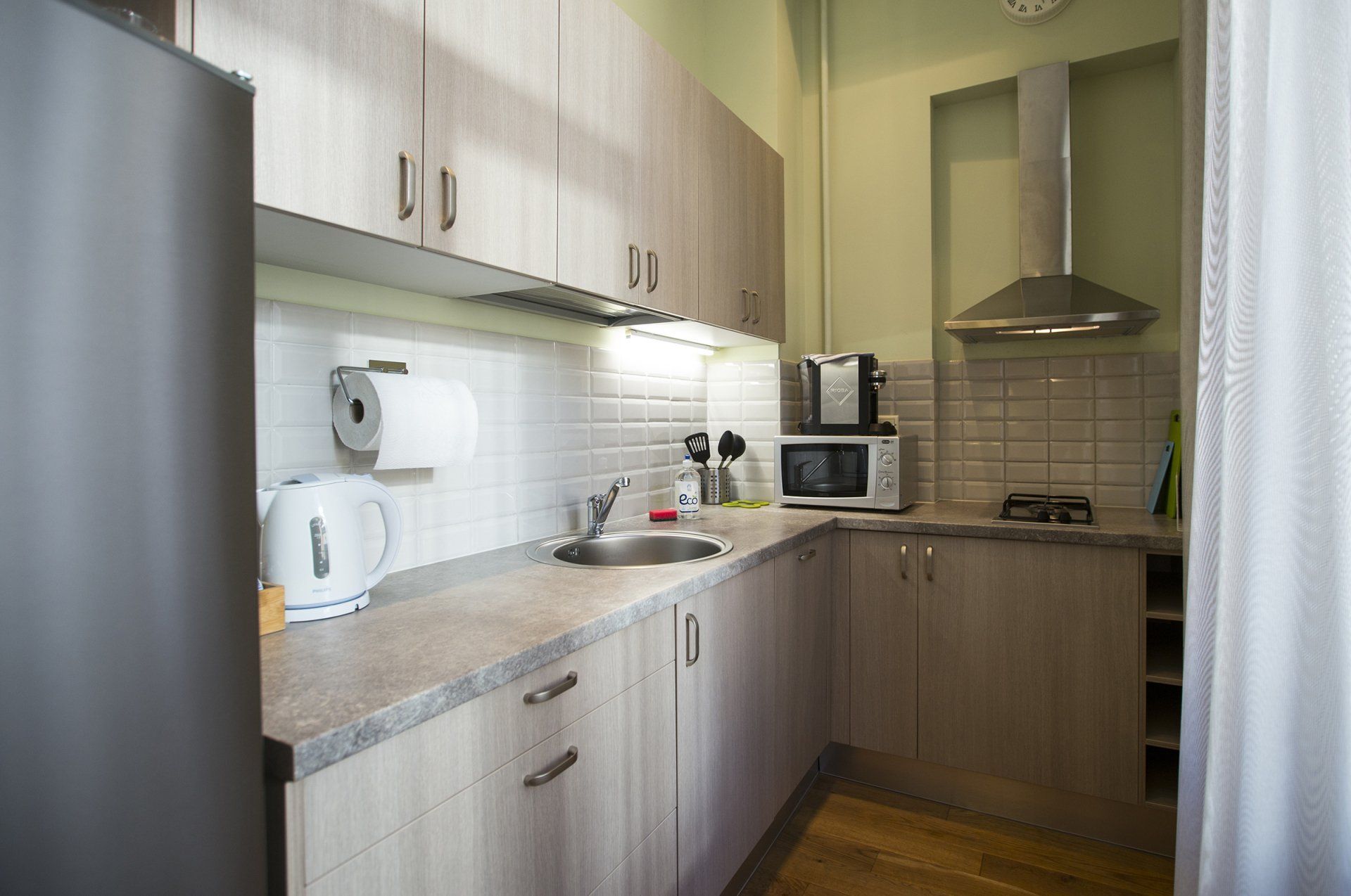 A kitchen with a sink , refrigerator , microwave and stove.