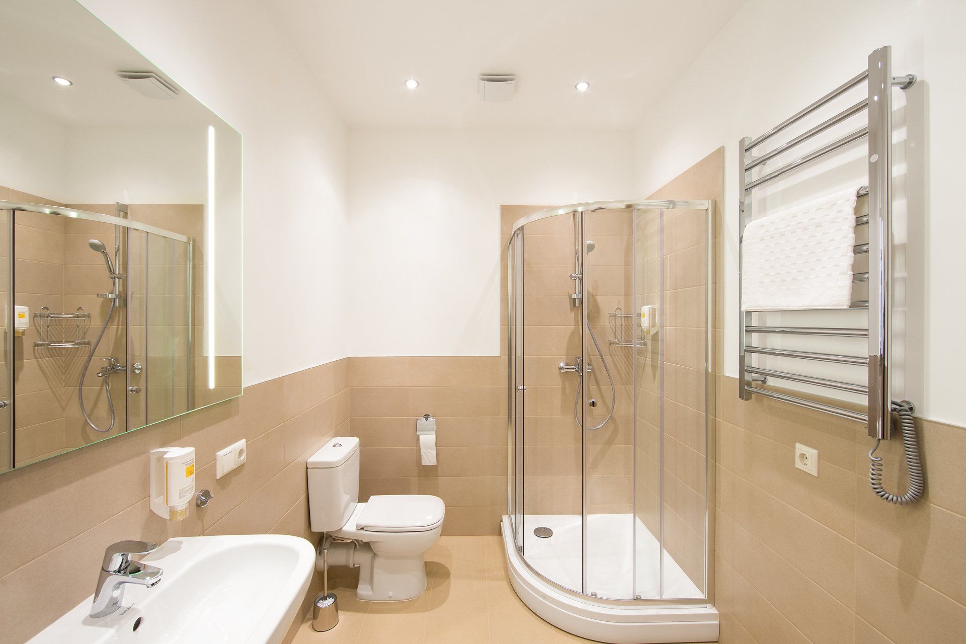 A bathroom with a toilet , sink , shower and mirror.