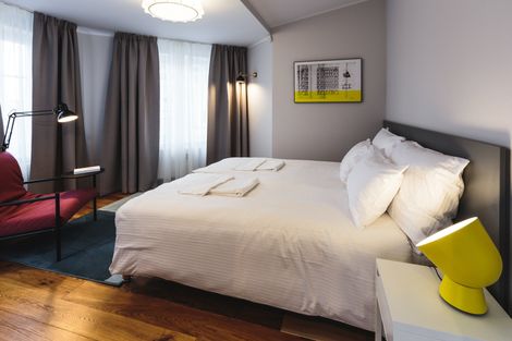 A hotel room with a king size bed and a red chair