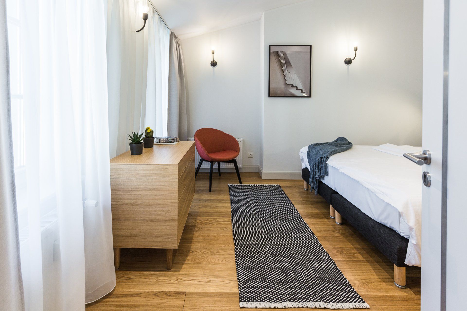 A bedroom with a bed , dresser , chair and rug.