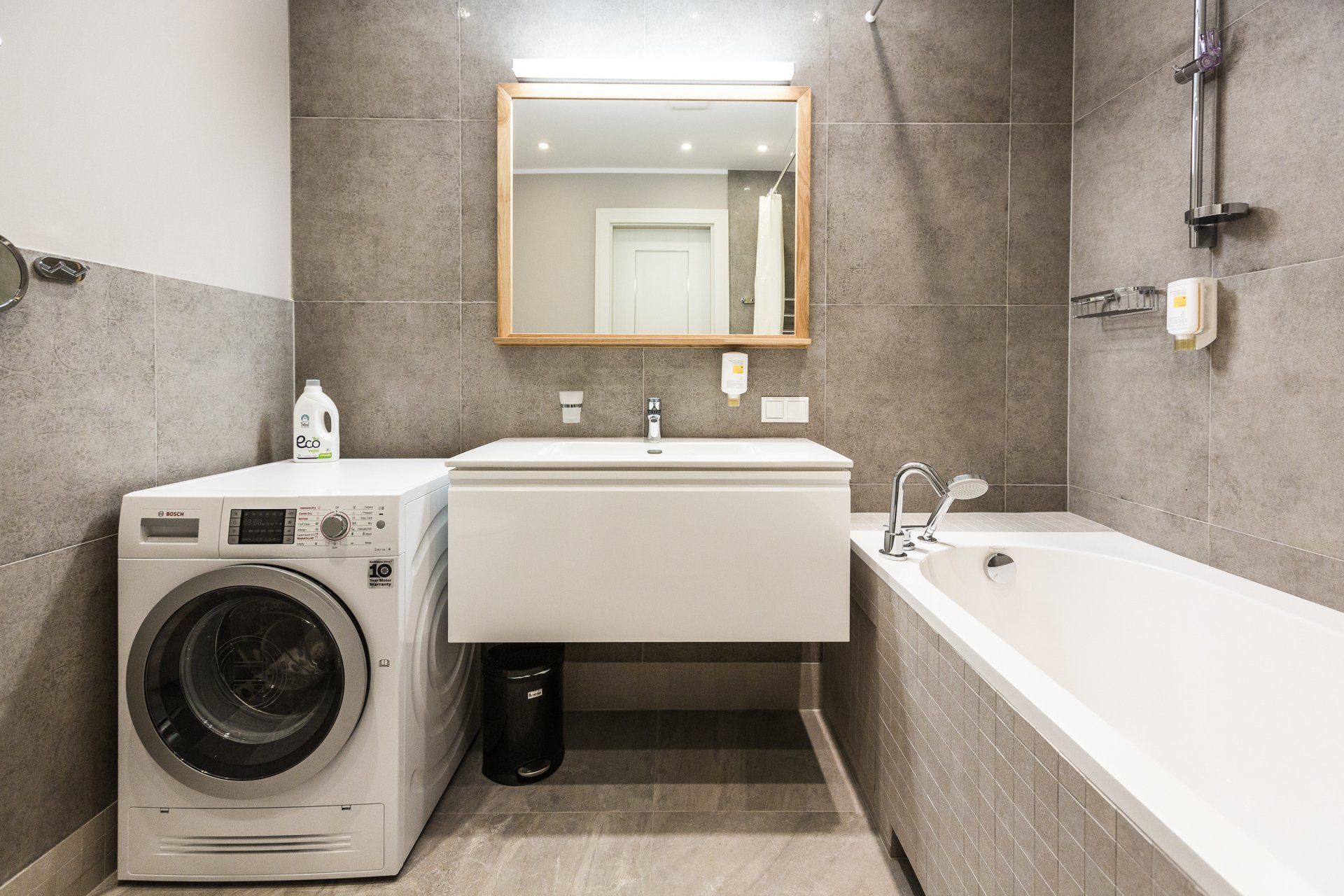 A bathroom with a washing machine , sink and bathtub.