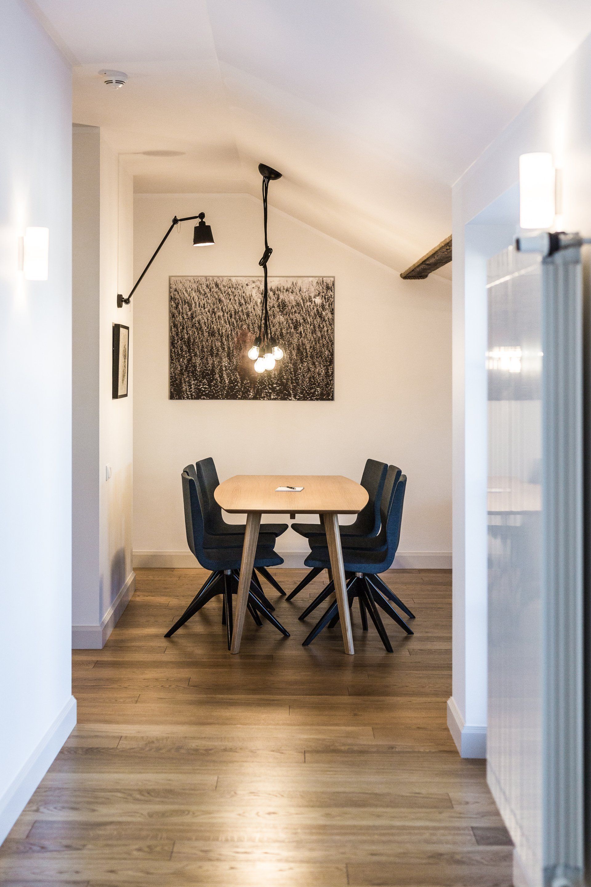 A dining room with a table and chairs and a picture on the wall.