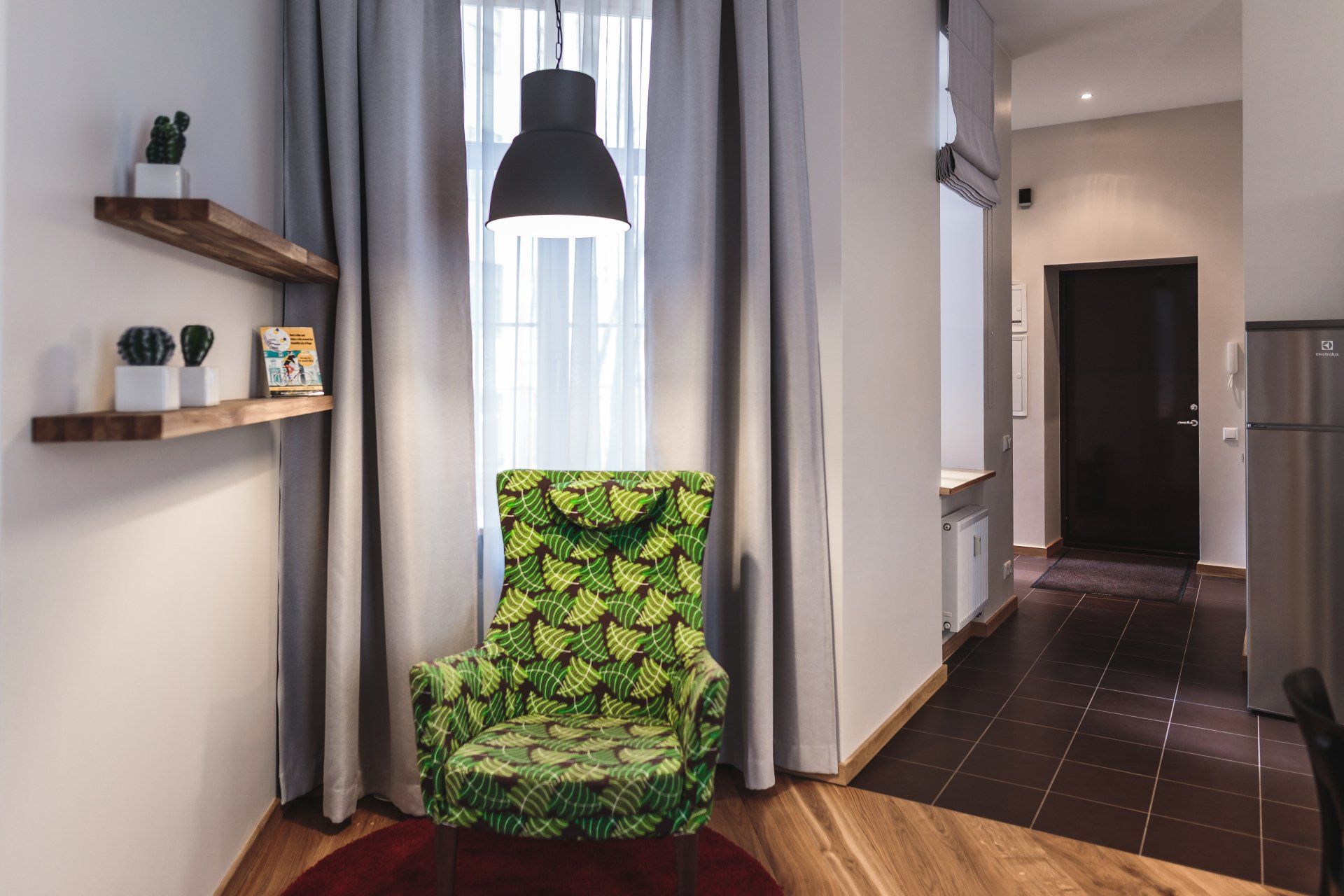 A green chair is sitting in a living room next to a window.