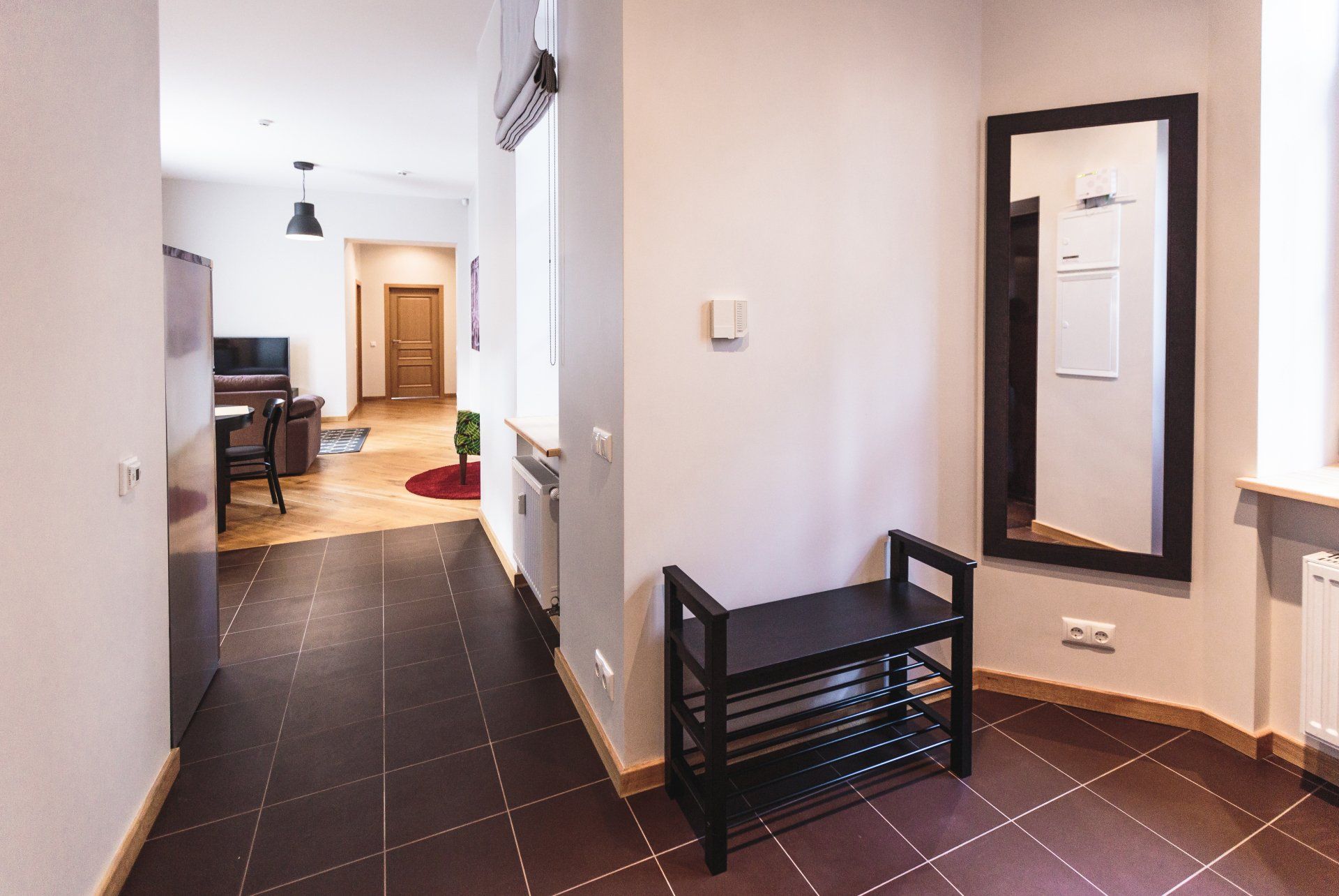 A hallway with a bench and a mirror on the wall.