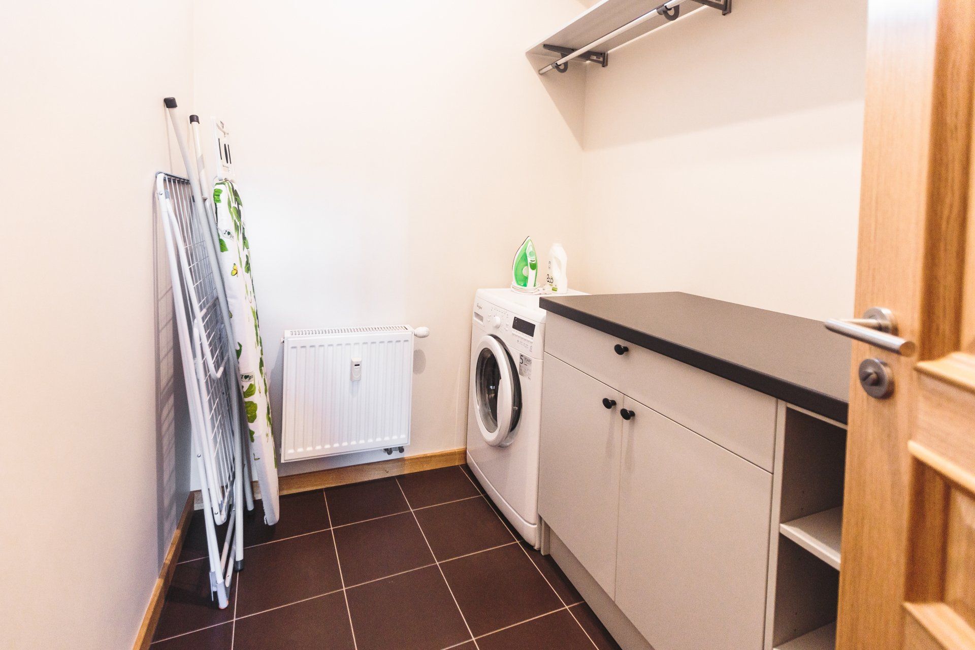 A laundry room with a washing machine and drying rack.