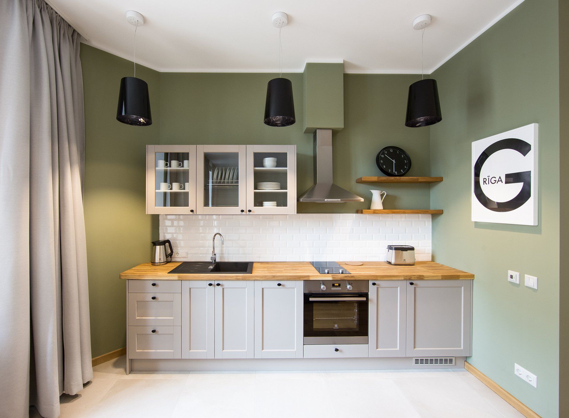 A kitchen with gray cabinets , wooden counter tops , stainless steel appliances and green walls.
