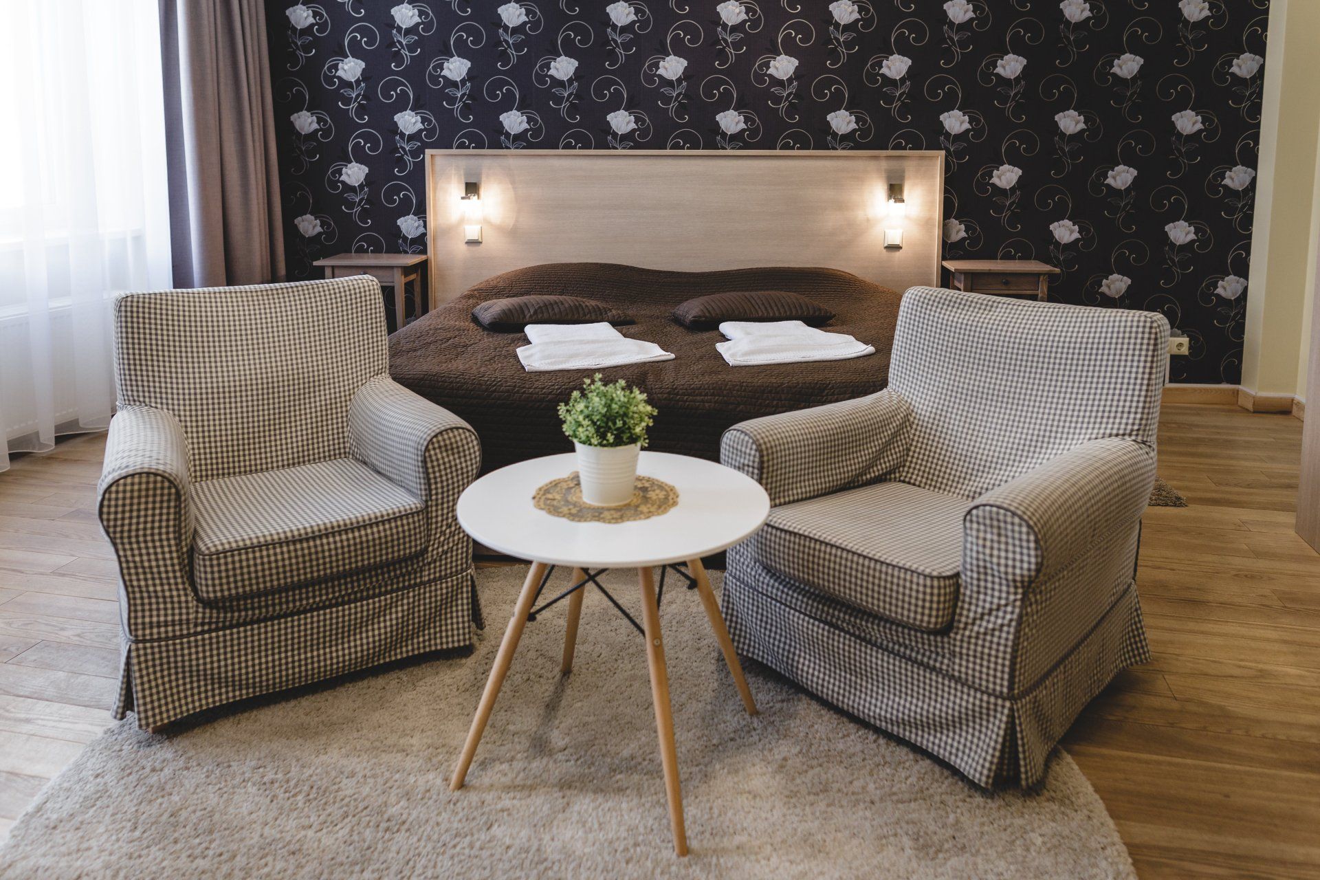 A hotel room with two chairs and a table in front of a bed.