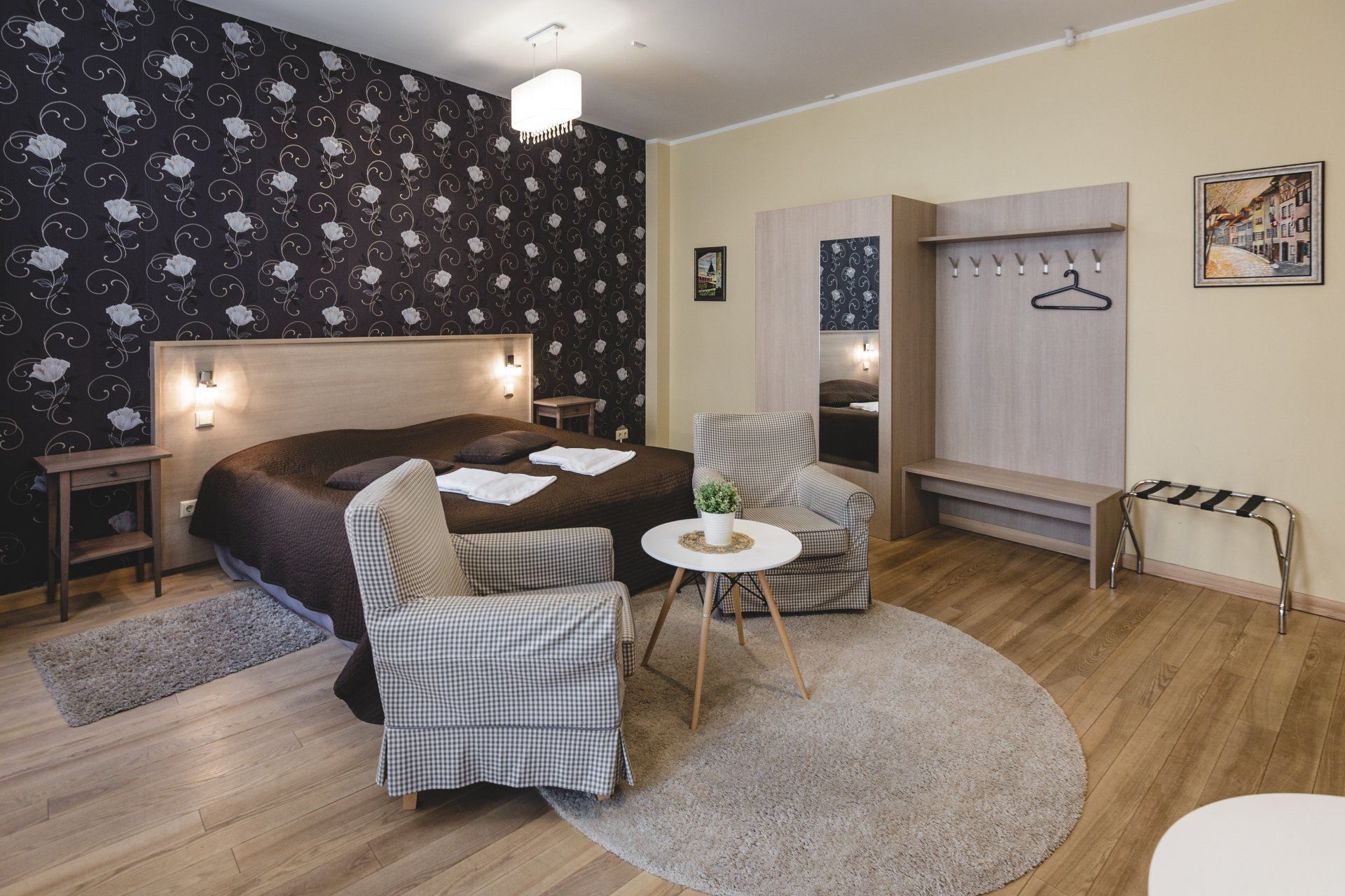A hotel room with a bed , chairs , a table and a rug.