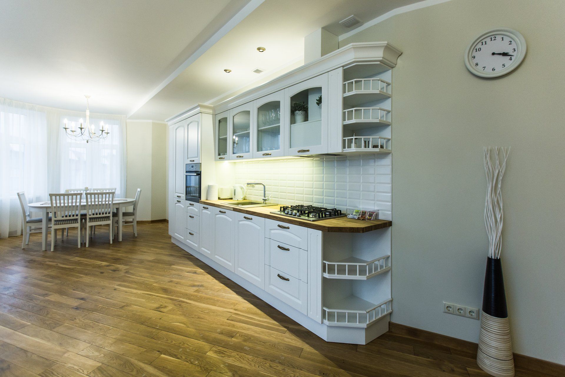 A kitchen with white cabinets and a clock on the wall.