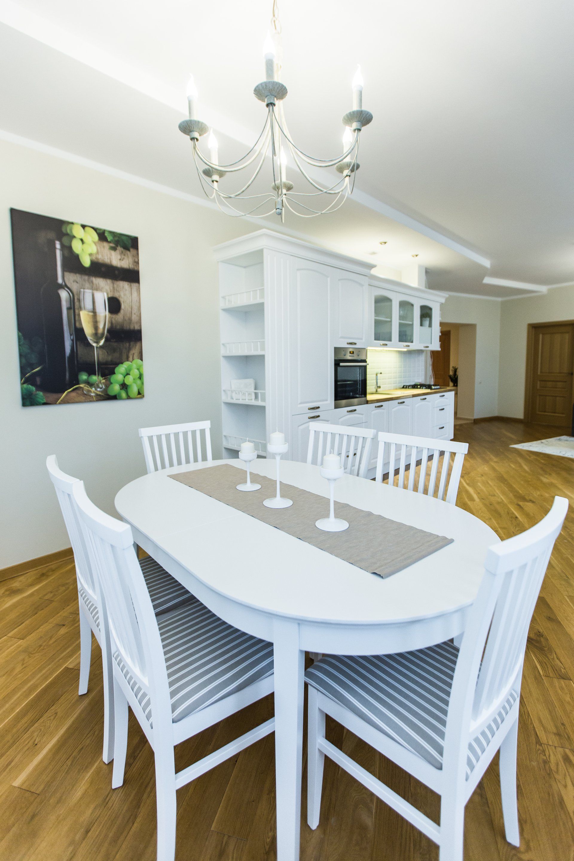 A dining room with a white table and chairs and a chandelier.