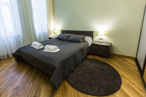 A bedroom with a bed , nightstand , and rug.