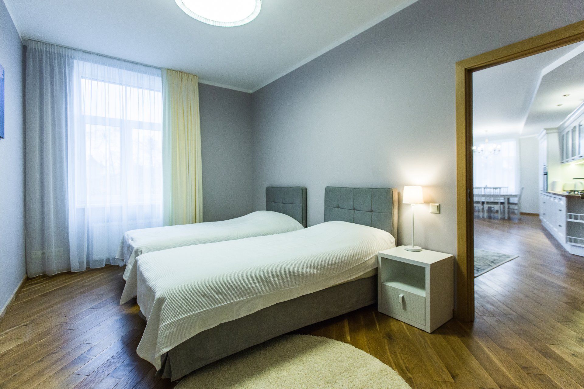 A bedroom with two beds , a nightstand and a window.