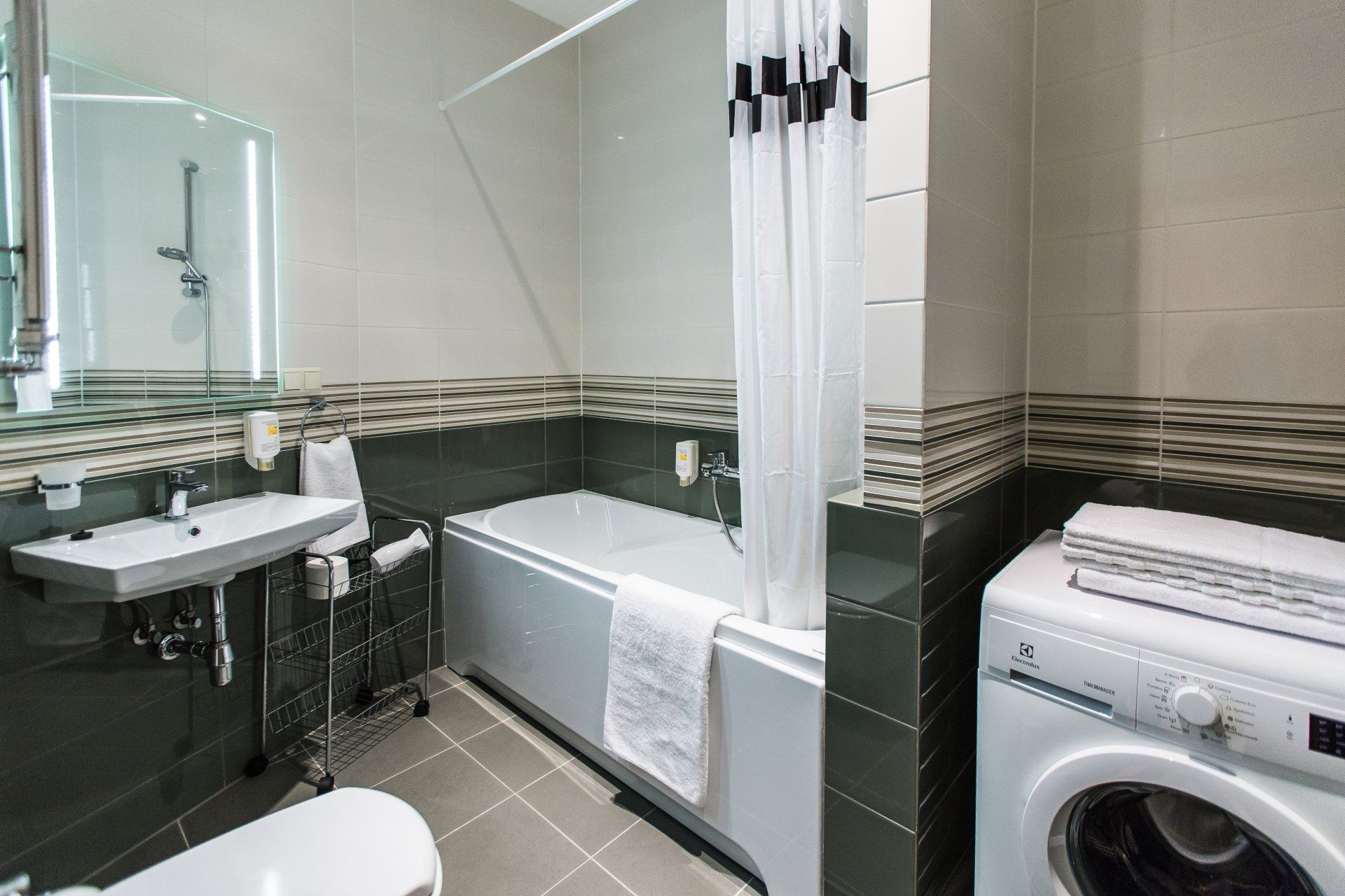 A bathroom with a bathtub , sink , toilet and washing machine.