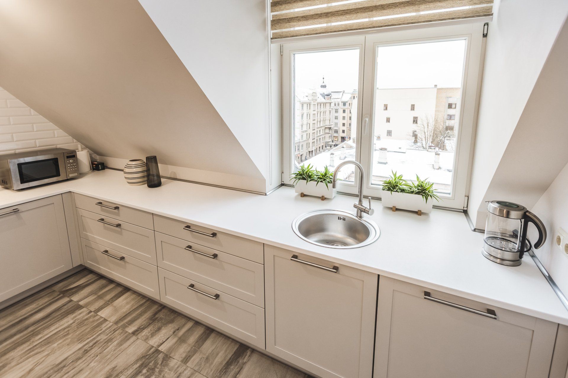 A kitchen with white cabinets , a sink , and a window.