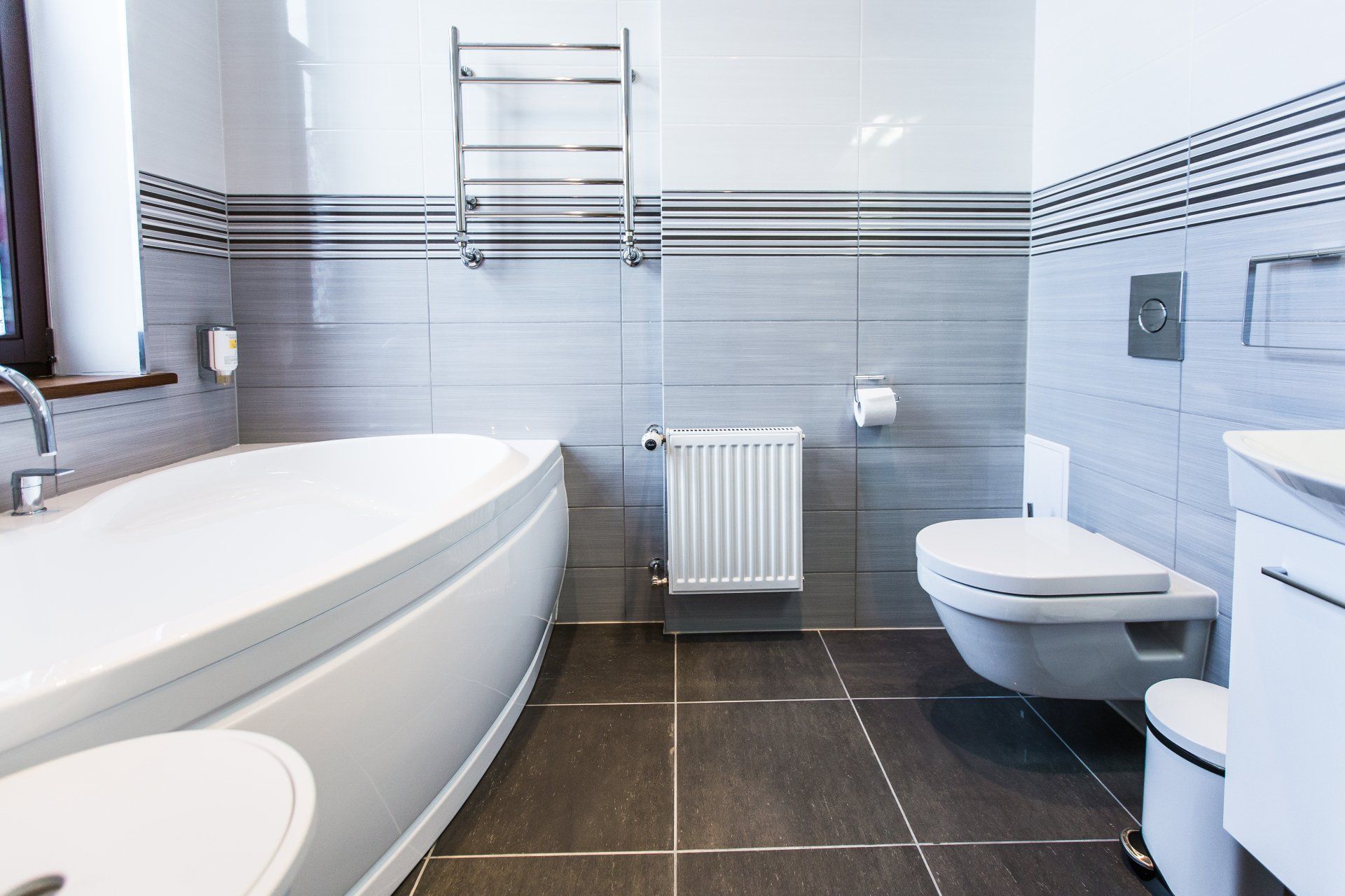A bathroom with a bathtub , toilet , sink and window.