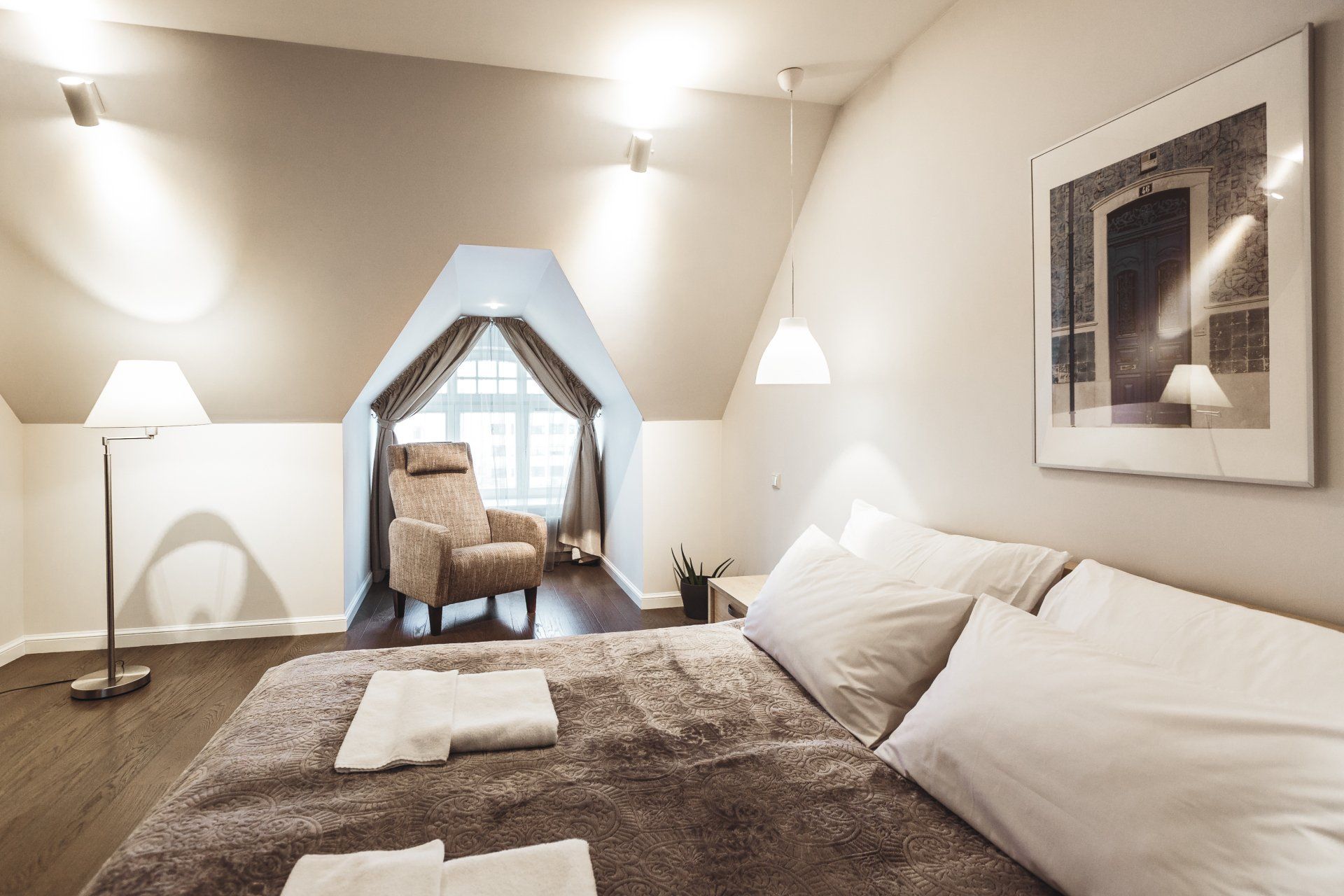 A bedroom with a bed , chair , lamp and picture on the wall.