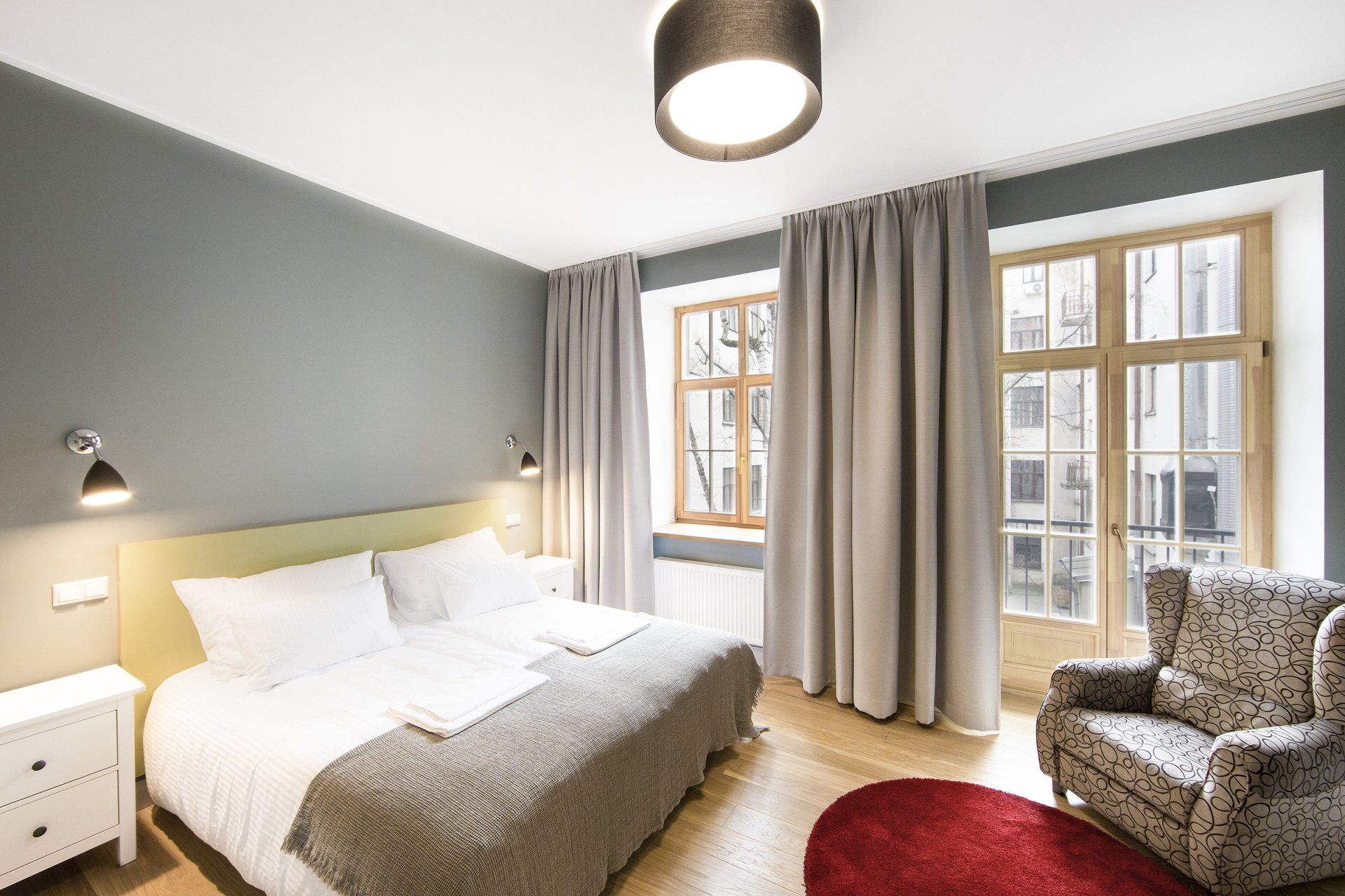 A bedroom with a bed , chair , nightstand and window.