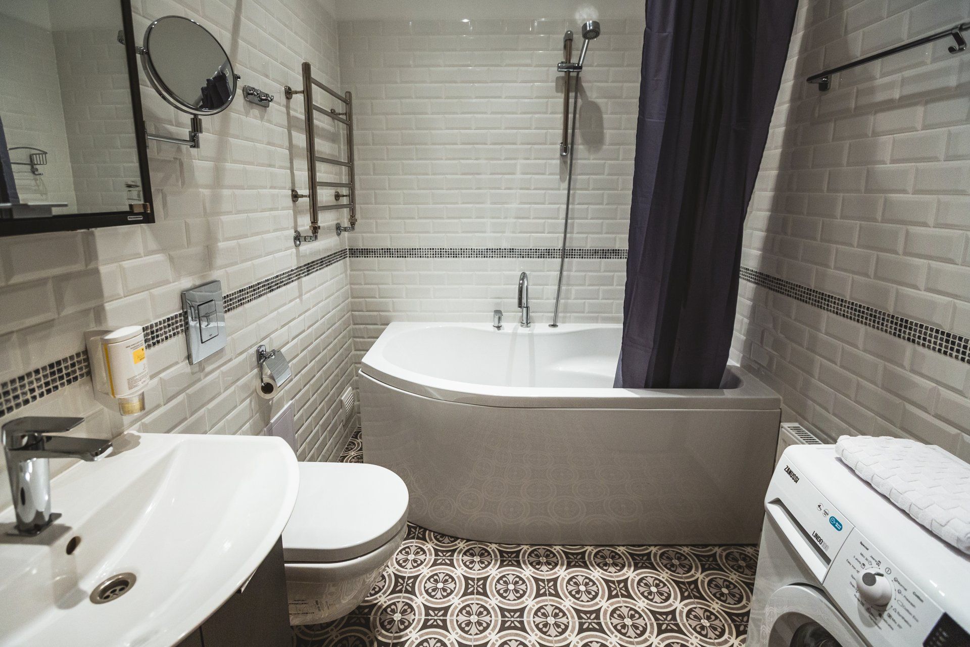 A bathroom with a bathtub , toilet , sink and washing machine.
