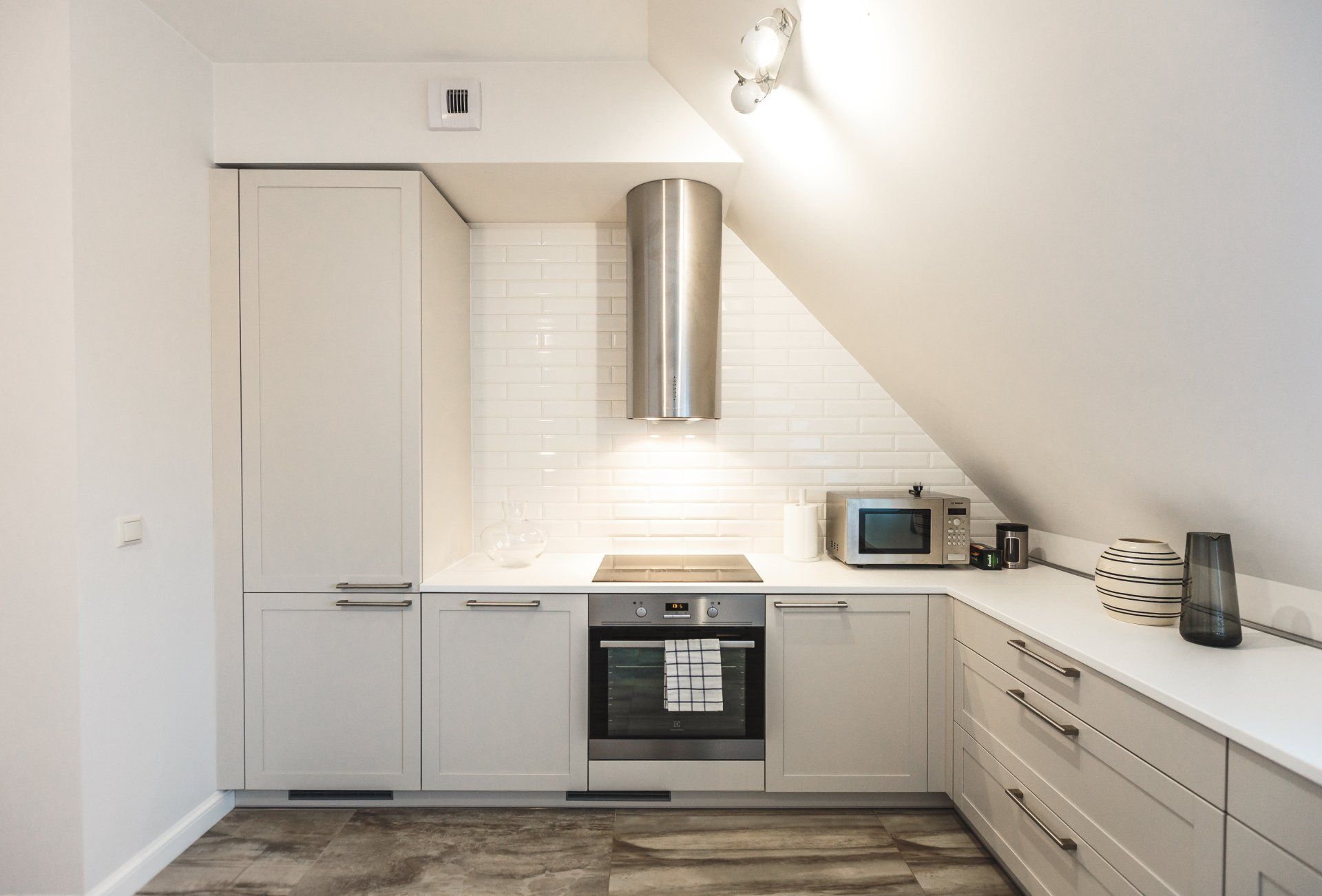A kitchen with white cabinets , a stove , a microwave and a hood.