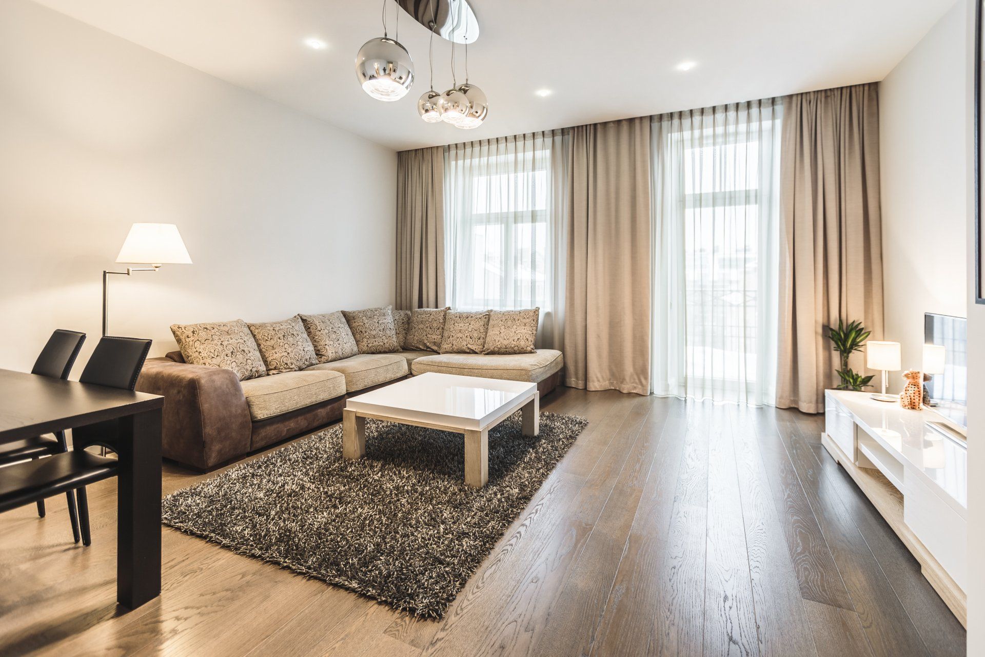 A living room with a couch , table , chairs and curtains.