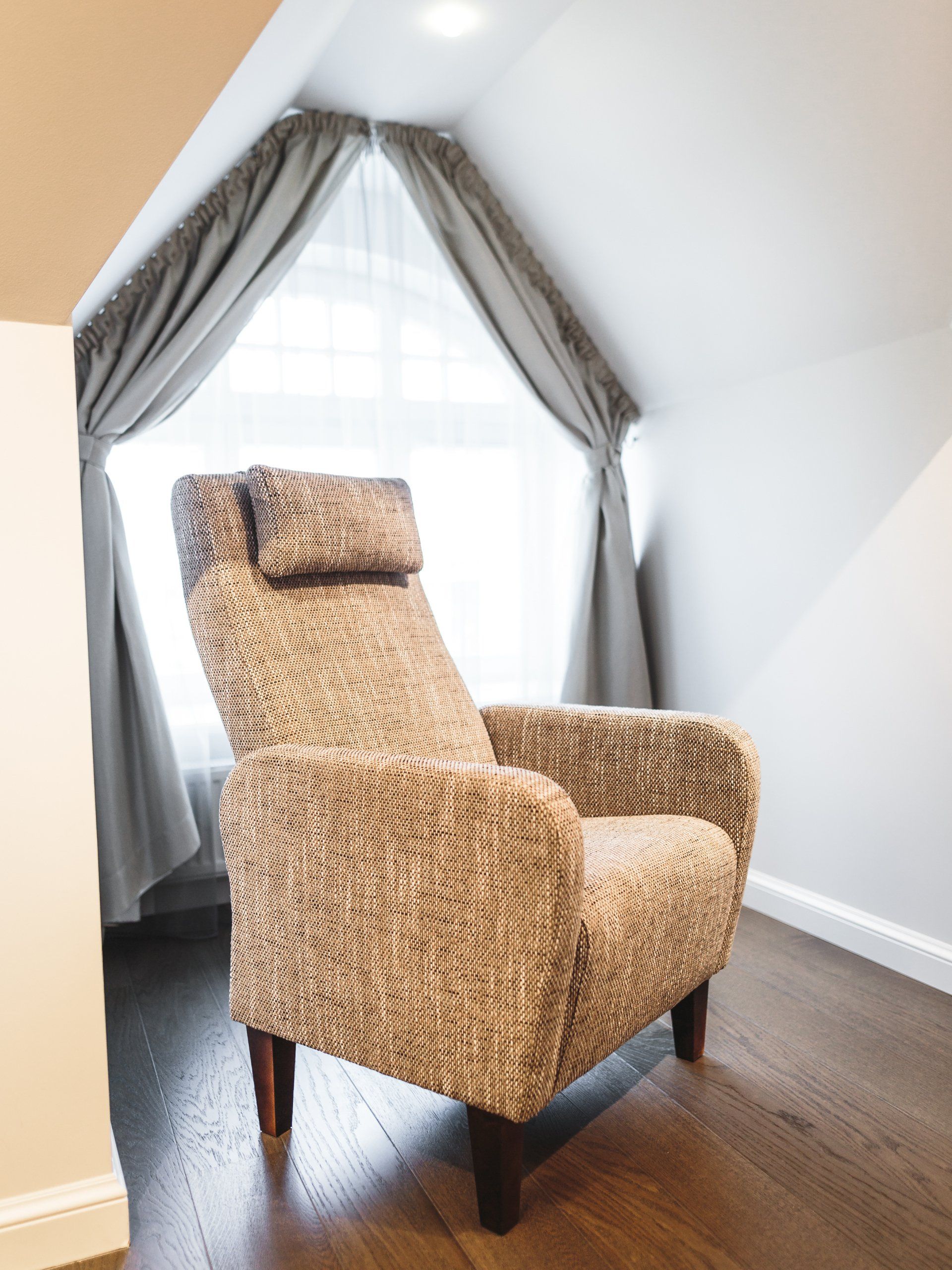A chair in a room with a window and curtains