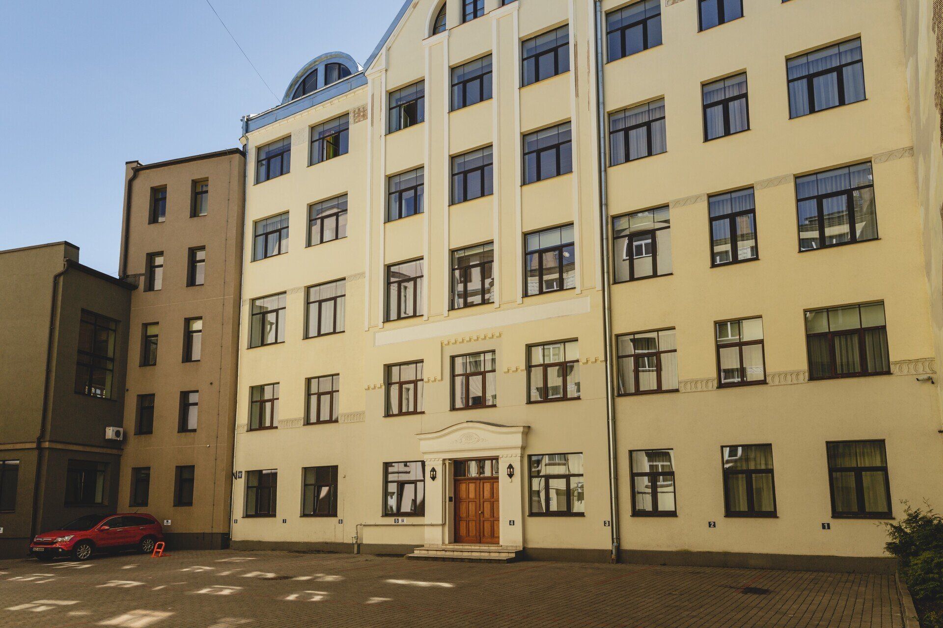 A large building with a lot of windows and a red car parked in front of it
