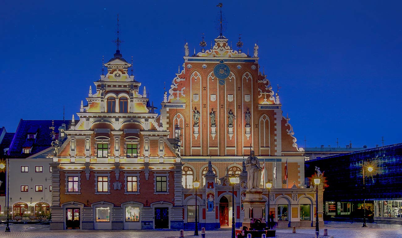 A large building with a clock on top of it is lit up at night.