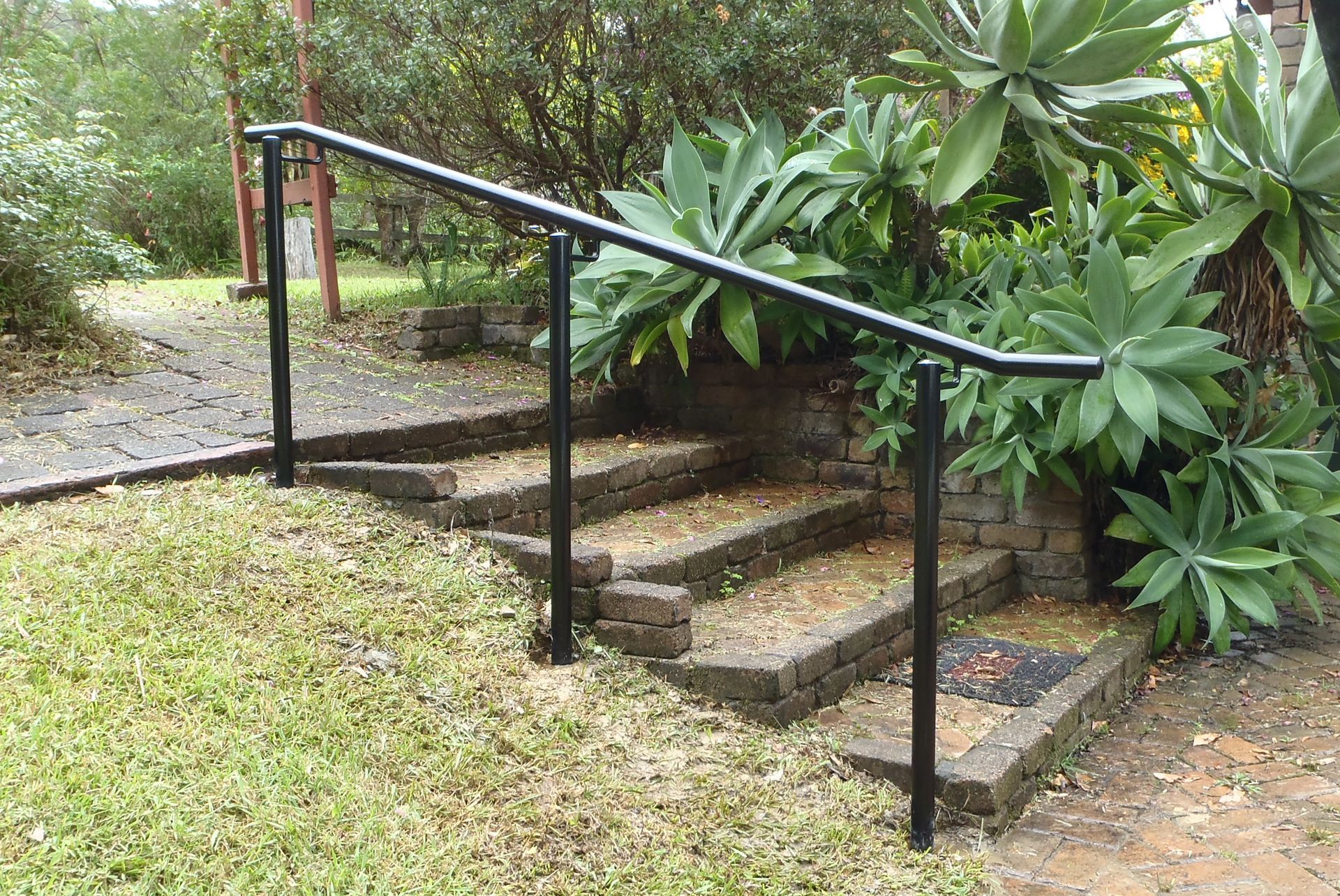 A black railing surrounds a set of stairs in a garden — Fabricator In Coffs Harbour, NSW