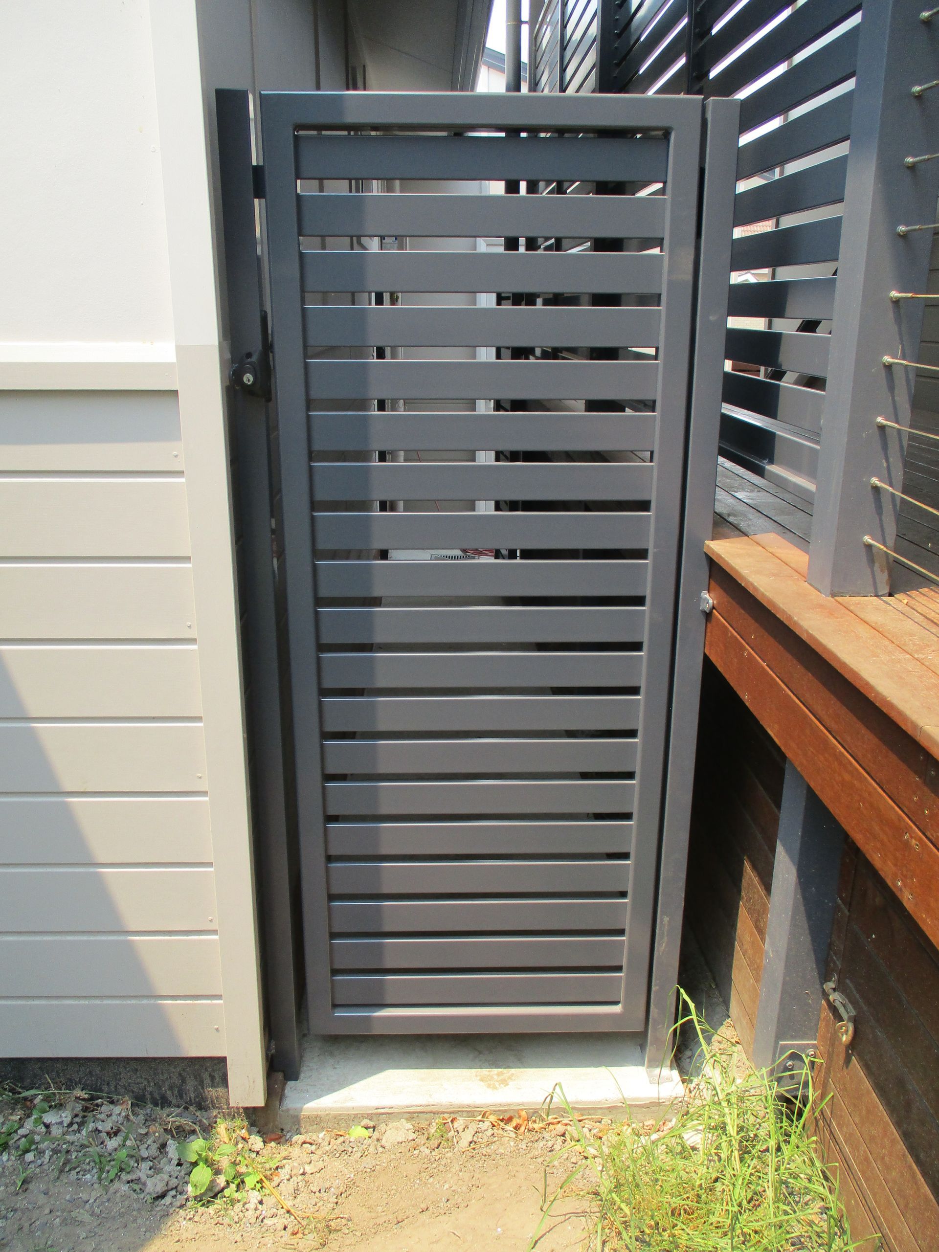 A gray metal gate is sitting in front of a building — Fabricator In Coffs Harbour, NSW