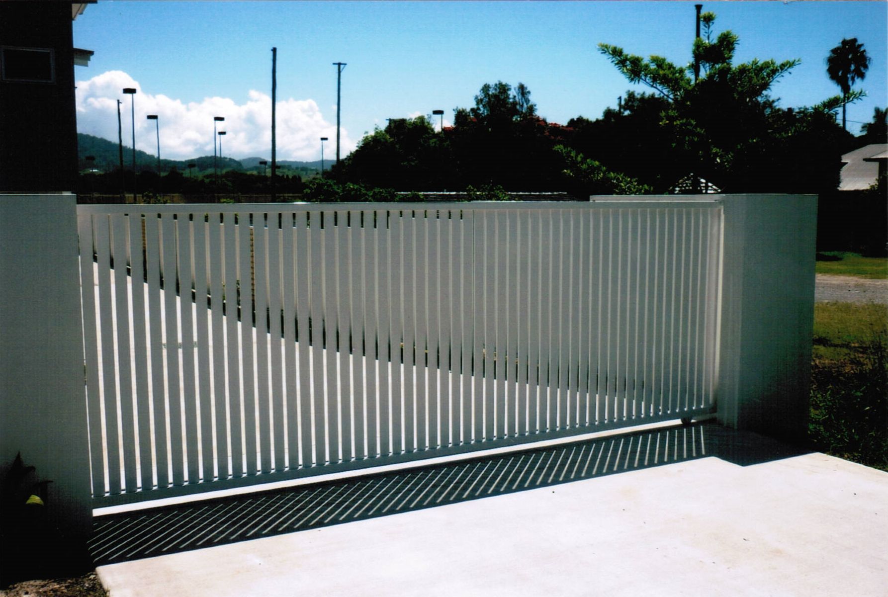 A white sliding gate is open to a driveway — Fabricator In Coffs Harbour, NSW