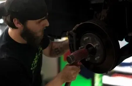 Mechanic working on a car wheel with a wrench in a dim garage