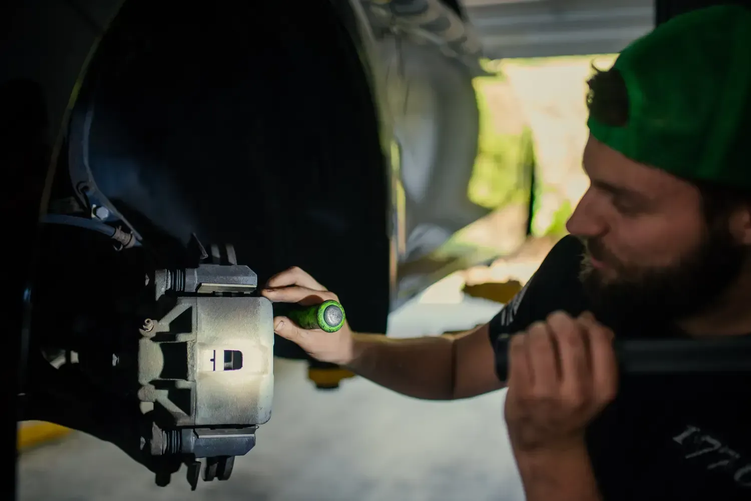 Zima mechanic in a black cap inspecting a white vehicle in a workshop
