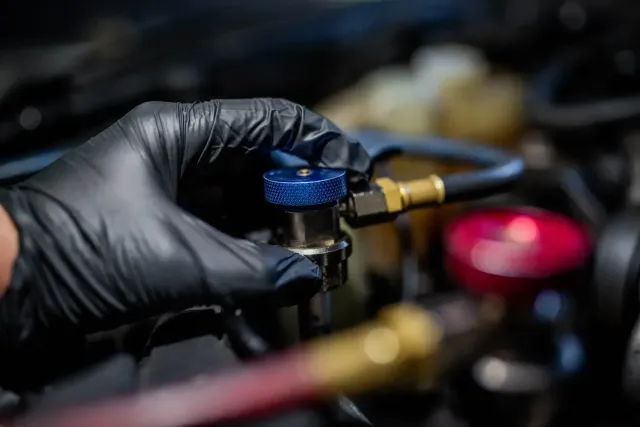Technician adjusting a red-and-black welding machine in a workshop, with cables and tools nearby