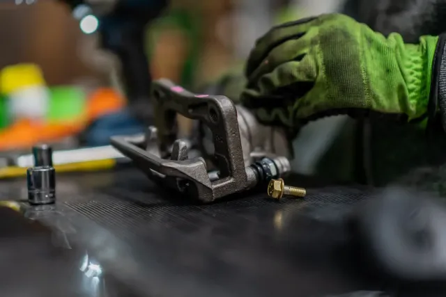 Mechanic using a tool to work on a car wheel hub in a garage