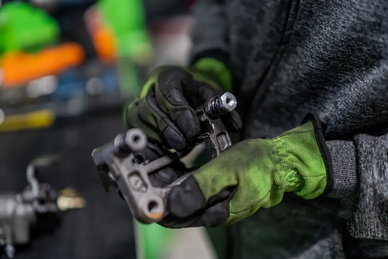 Mechanic using a wrench to work on a car’s wheel hub in a garage