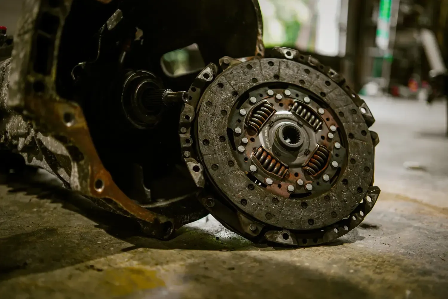 Mechanic’s gloved hands installing a clutch assembly under a car.